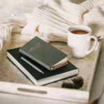 green journal and cup of coffee on a cream tray