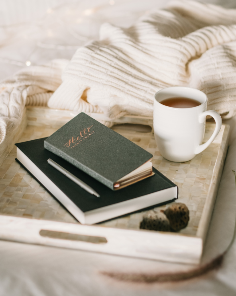 green journal and cup of coffee on a cream tray